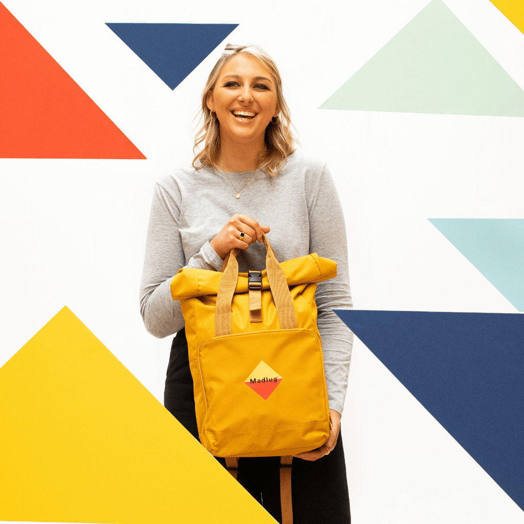 Madlug Roll-Top Backpack in Mustard. Modelled holding bag.