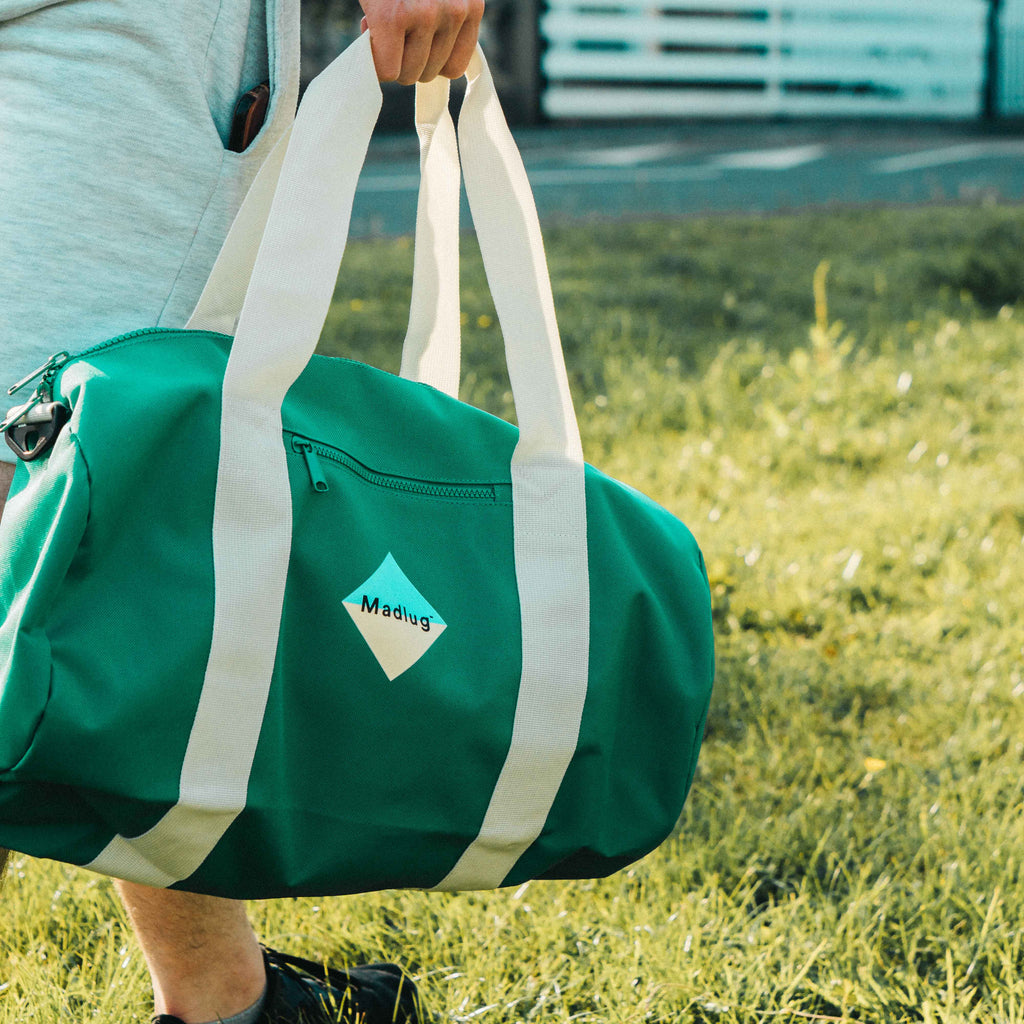 Madlug Duffel Bag in Green. Modelled showing rear view.